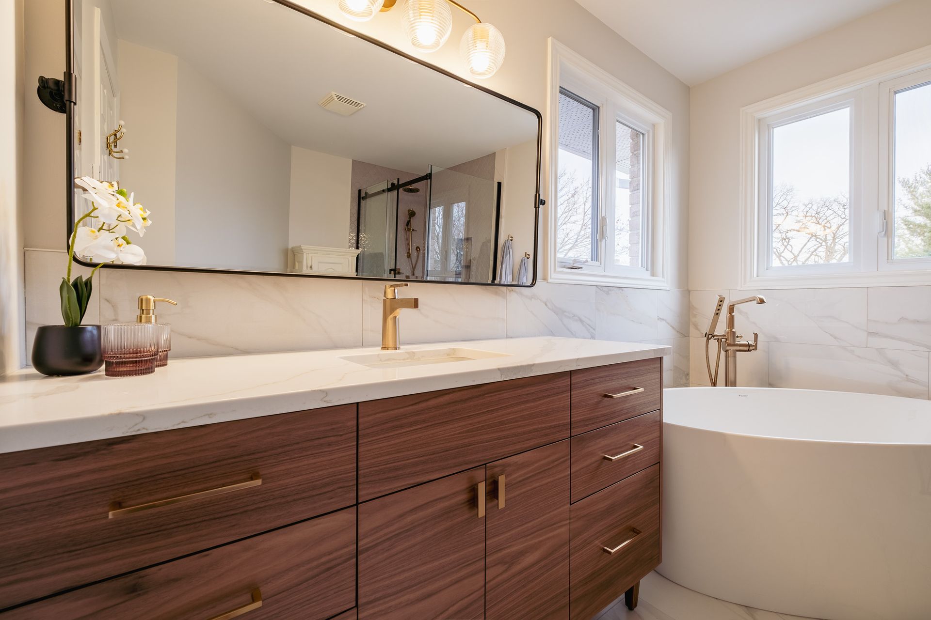 A bathroom with a sink, mirror, and bathtub.