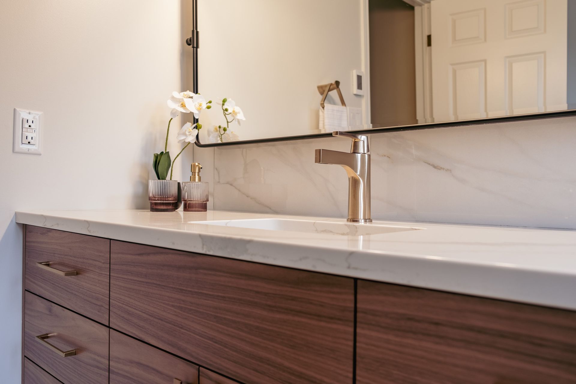 A bathroom with a sink, mirror and drawers.