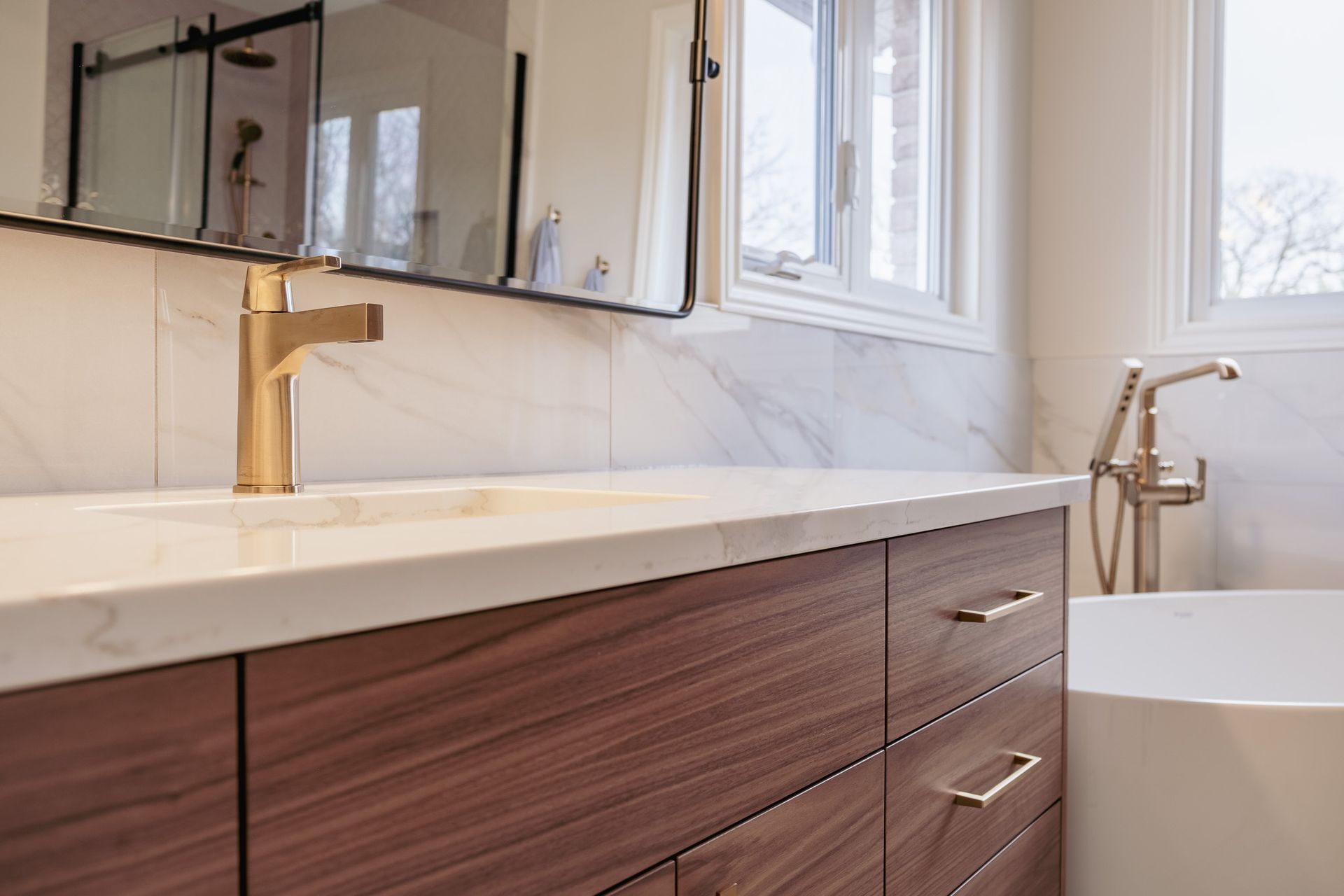 A bathroom with a sink, tub, and mirror.