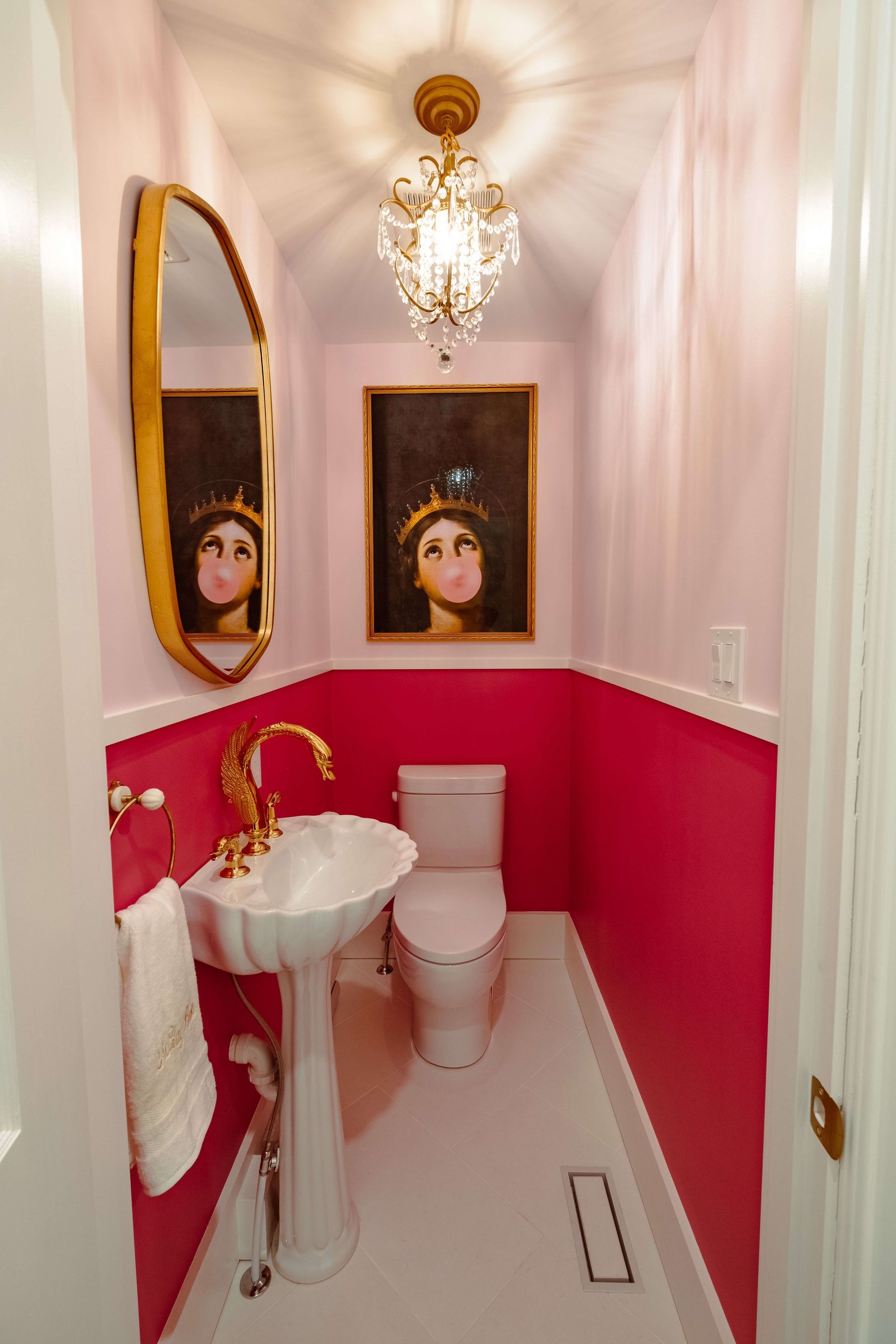 A bathroom with pink walls, a toilet, a sink and a mirror.