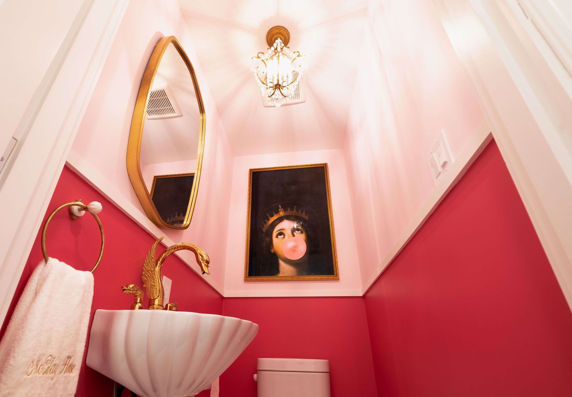 A bathroom with a sink, toilet, mirror and painting on the wall.