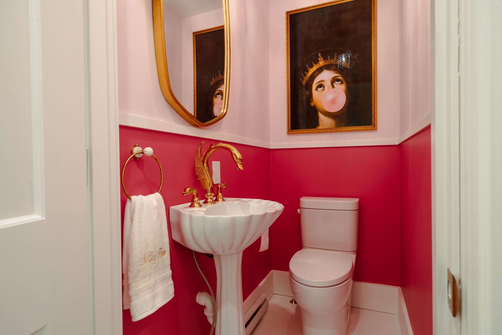 A bathroom with pink walls, a toilet, a sink and a mirror.
