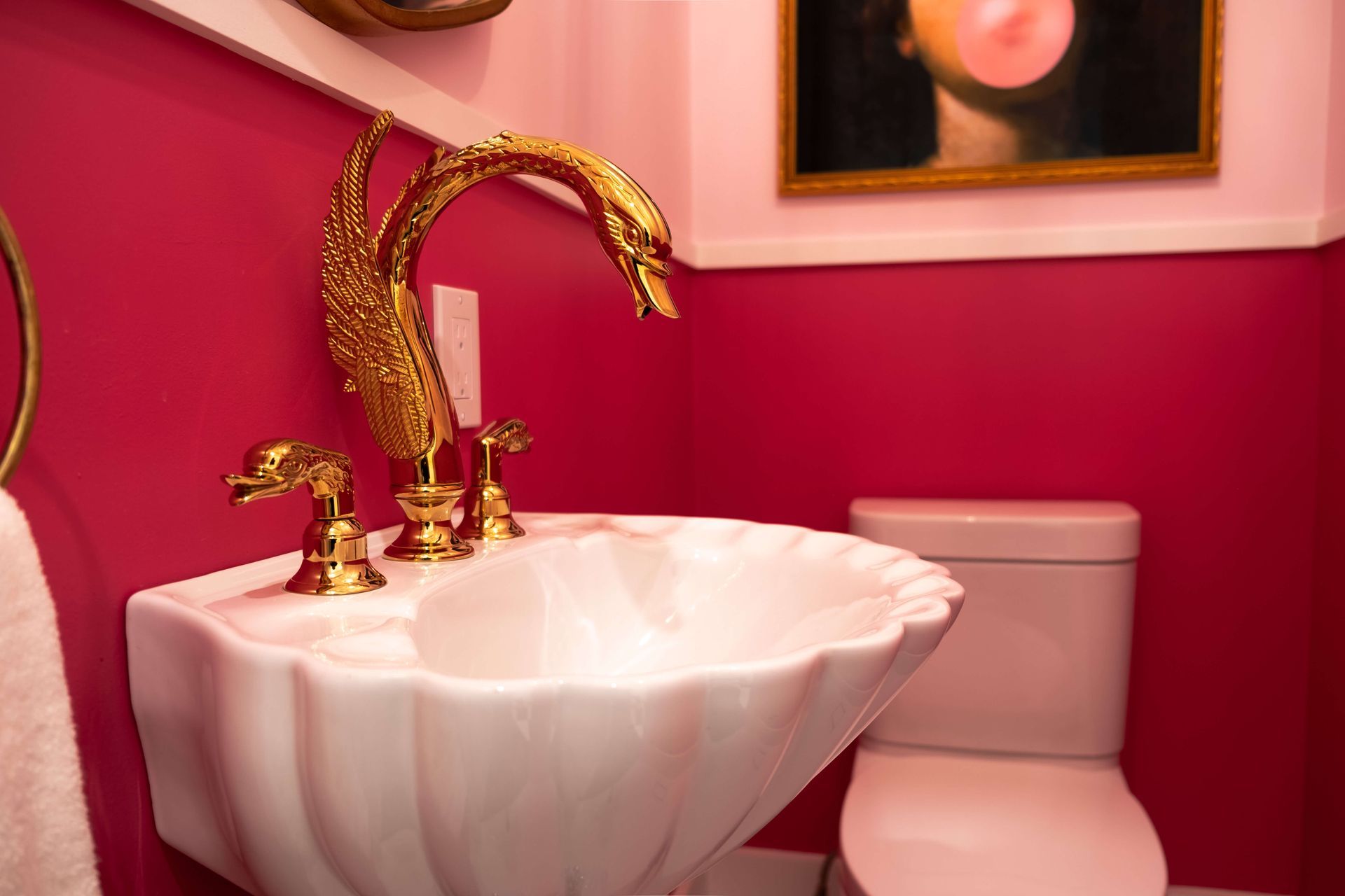 A bathroom with pink walls, a sink and toilet.