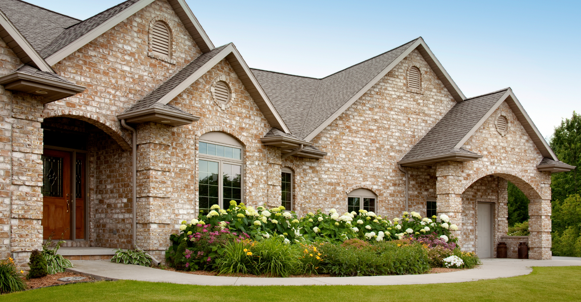 A large brick house with a lush green lawn in front of it