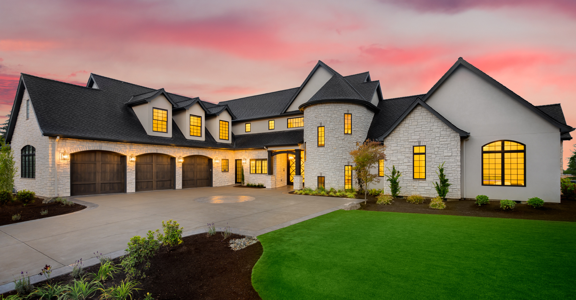 A large white house with a black roof is sitting on top of a lush green lawn.