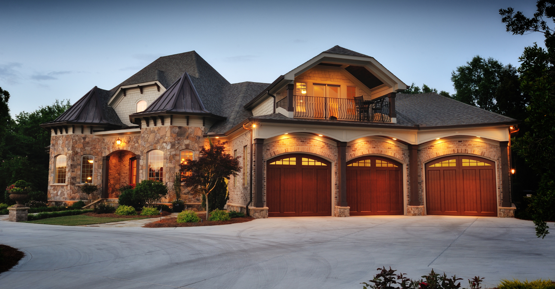 A large house with three garage doors is lit up at night