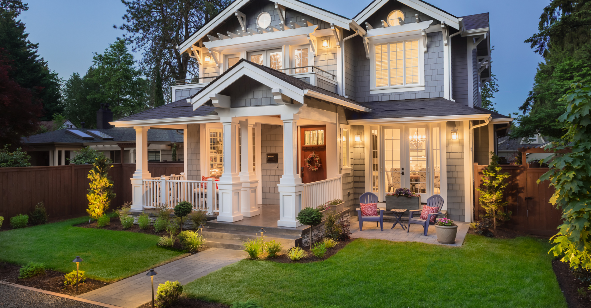 A large house with a large porch is lit up at night.