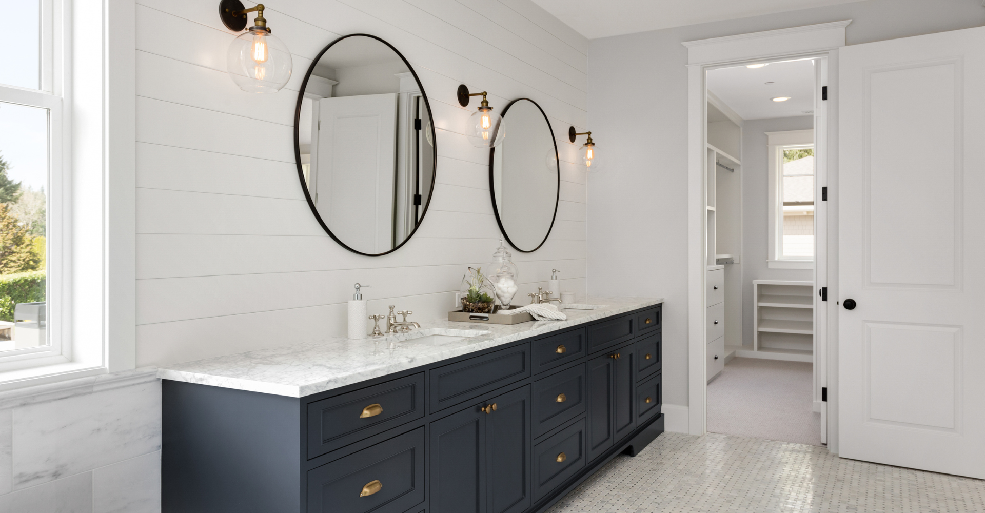 A bathroom with two sinks , two mirrors , and a walk in closet.