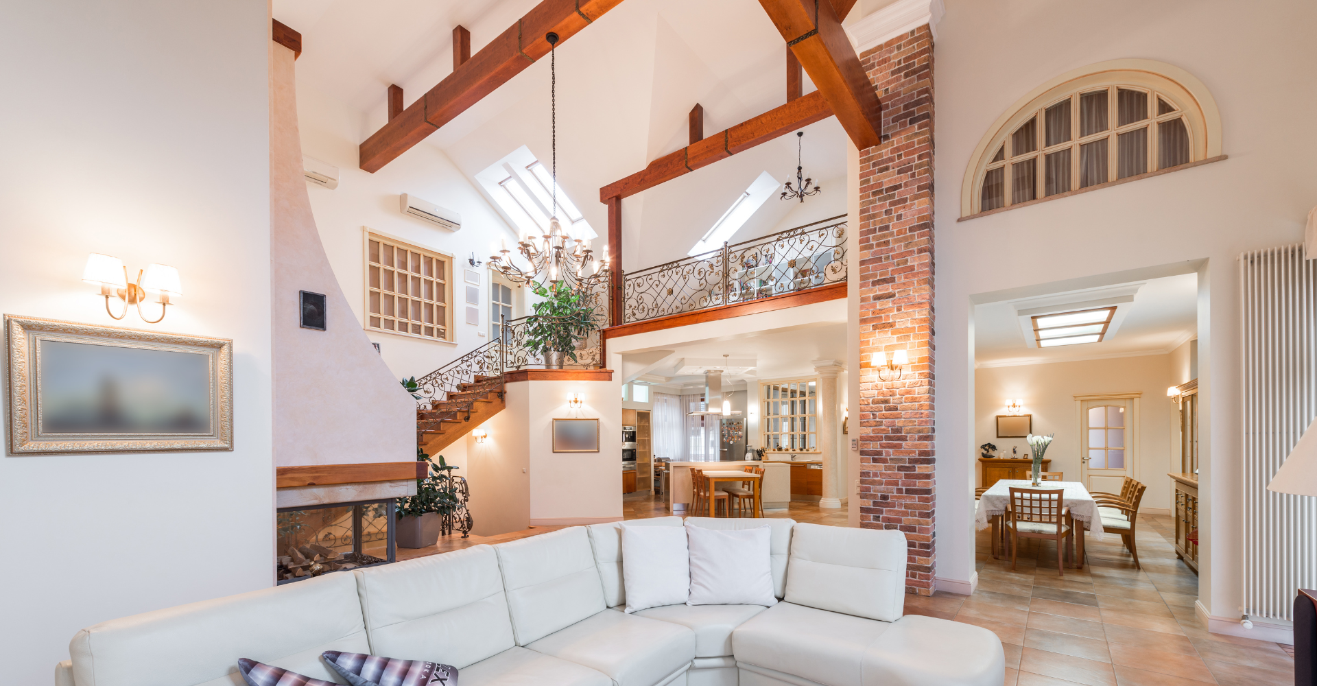 A living room with a white sectional couch and a fireplace.