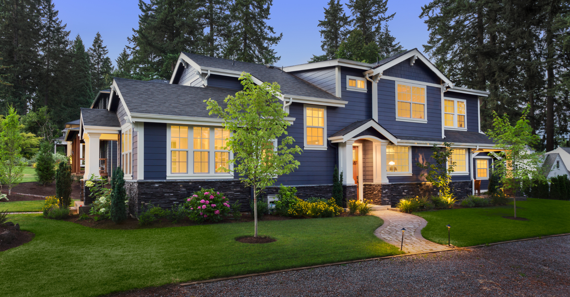 A large blue and white house with lots of windows is sitting on top of a lush green lawn.