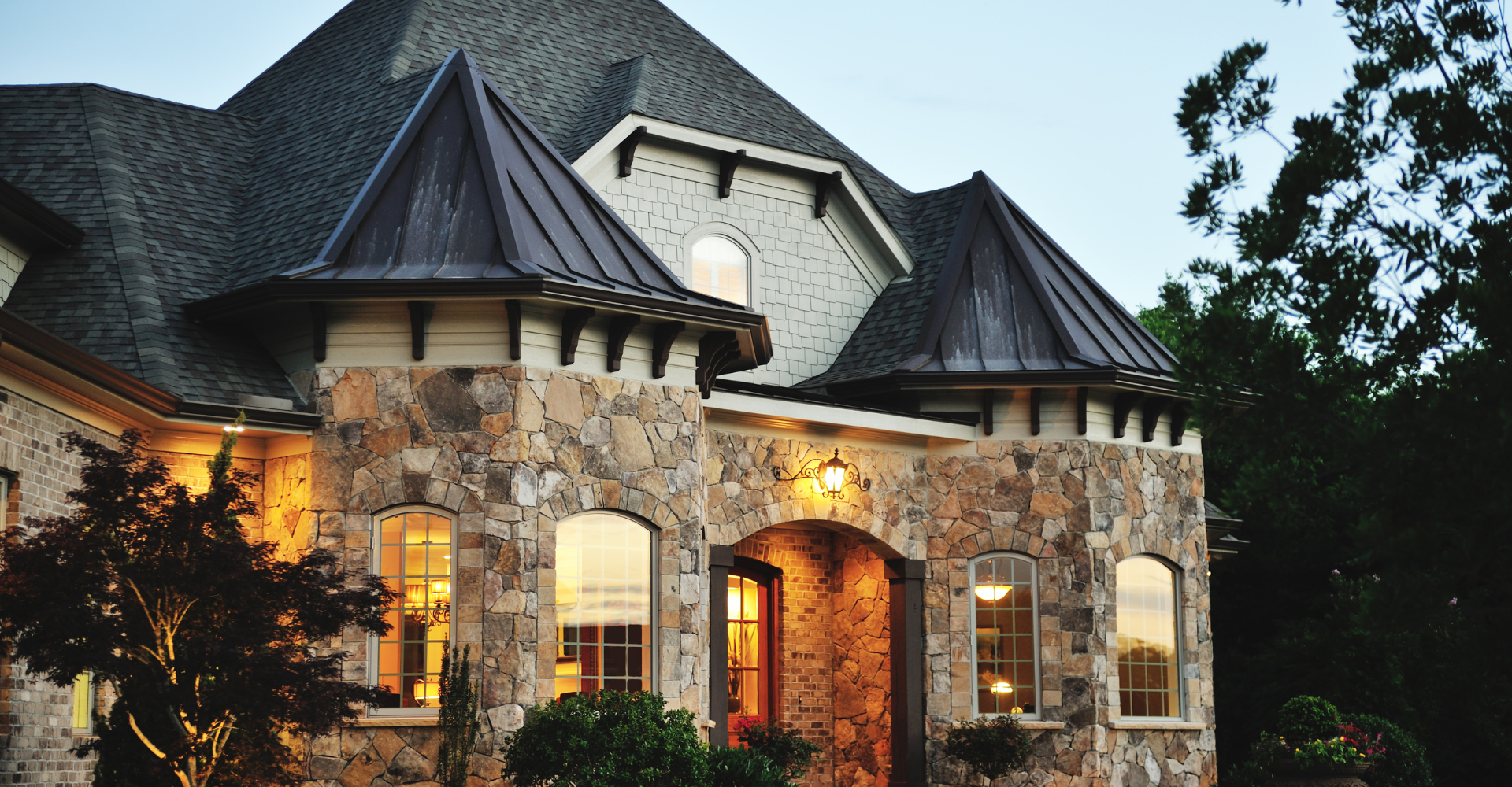 A large stone house with a metal roof is lit up at night