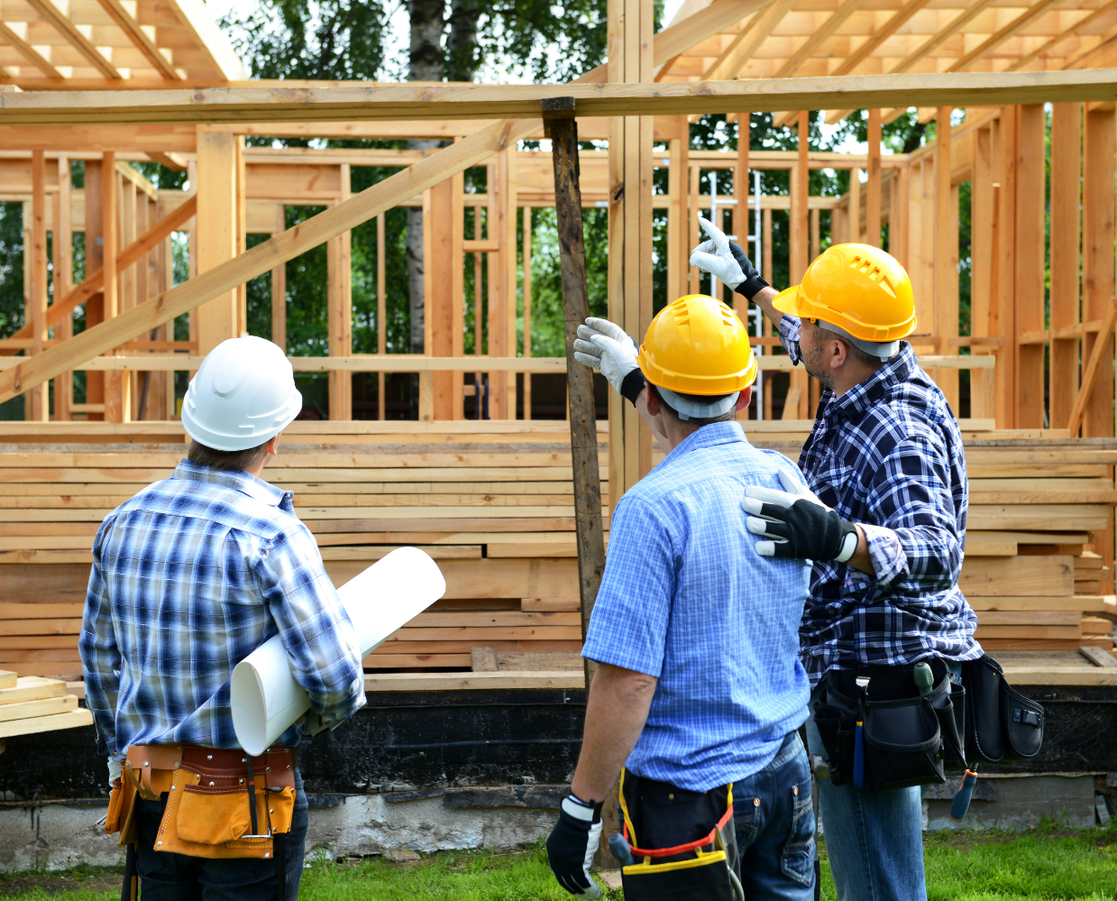 A group of construction workers are standing in front of a house under construction.