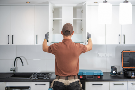 Compass Construction team member installing new cabinets as part of a Kitchen remodeling project