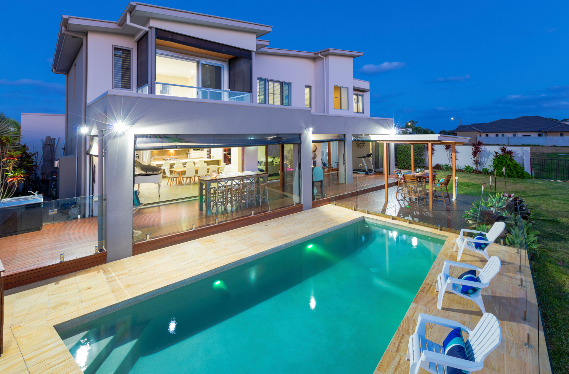 Custom luxury deck behind a massive mansion, customized to fit around a custom slender pool - backyard paradise