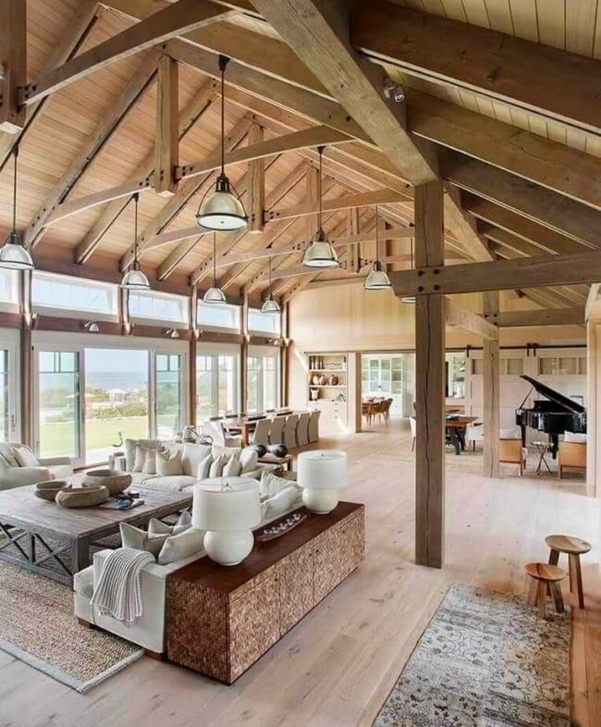 Large Barndominium Interior with living area, dining room, grand piano, and kitchen area. Sliding doors are slow shown leading out to a large deck and back yard