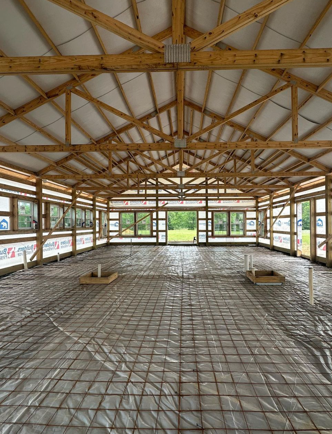 Large open interior of a barndominium as siding and insulation are added to the framing. 