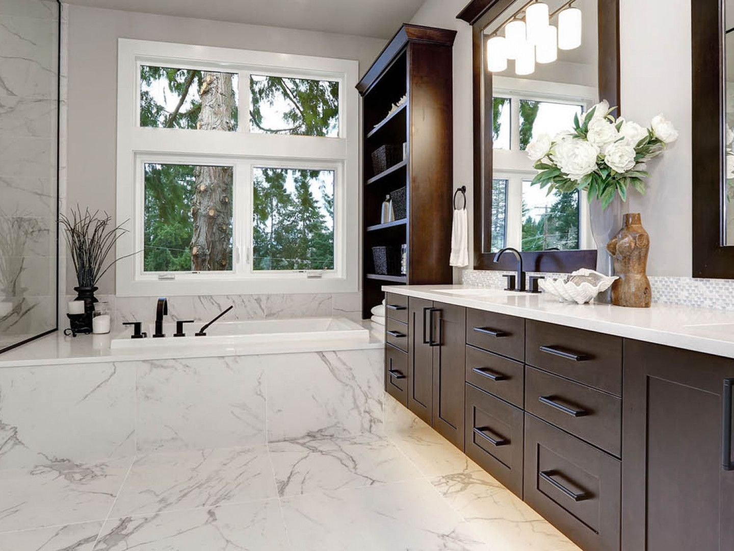 Beautiful modern bathroom with marble walls, granite countertops, gorgeous soft white lighting, brand new fixtures, and dark wood drawers, shelves, and cabinets. 