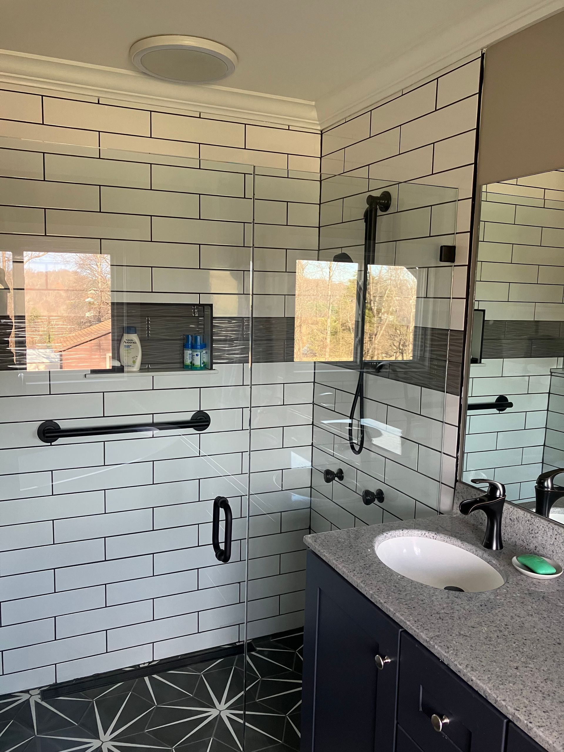 A bathroom with a sink , mirror and walk in shower.