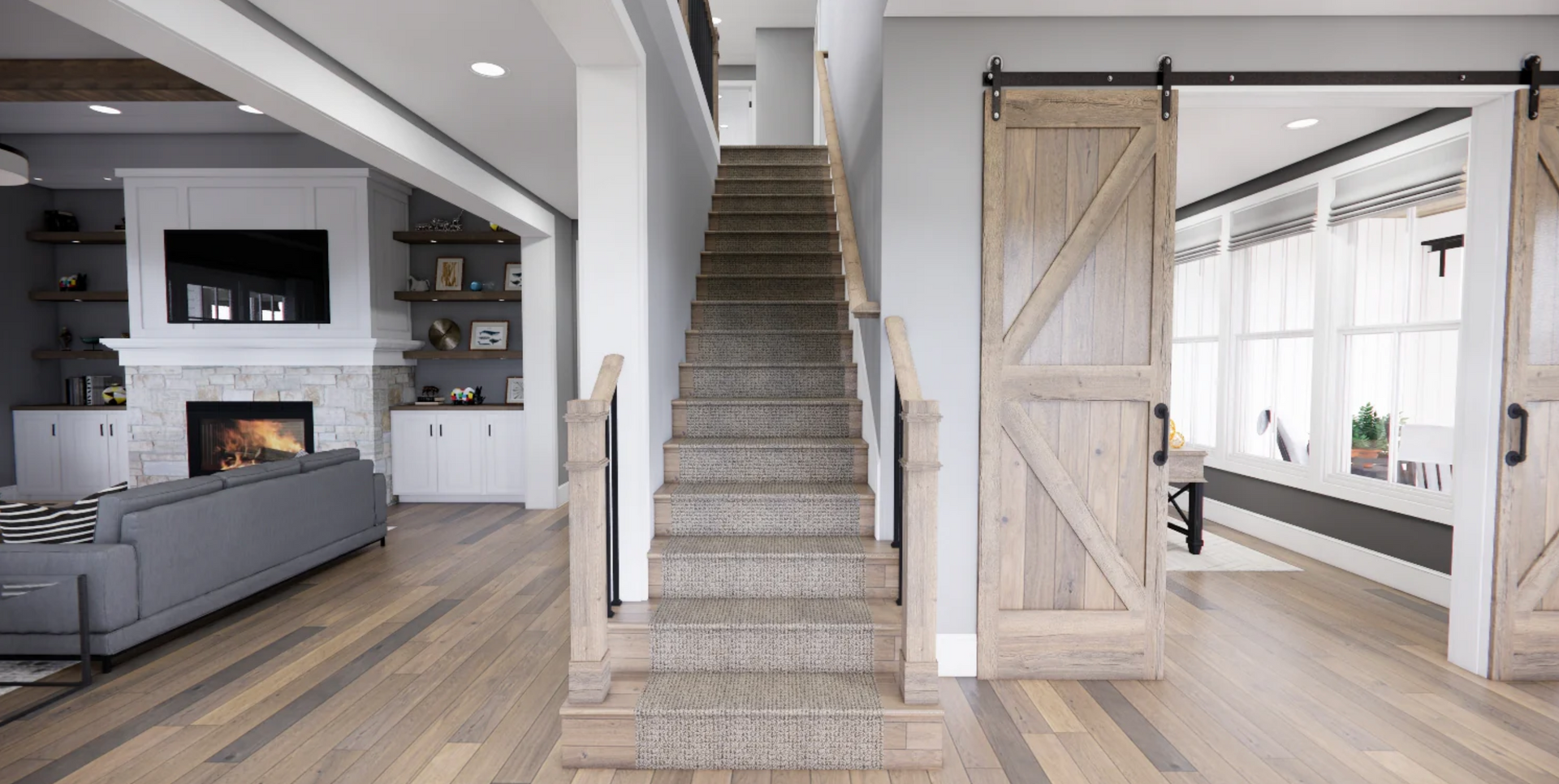 A living room with a staircase leading up to the second floor and a sliding barn door.