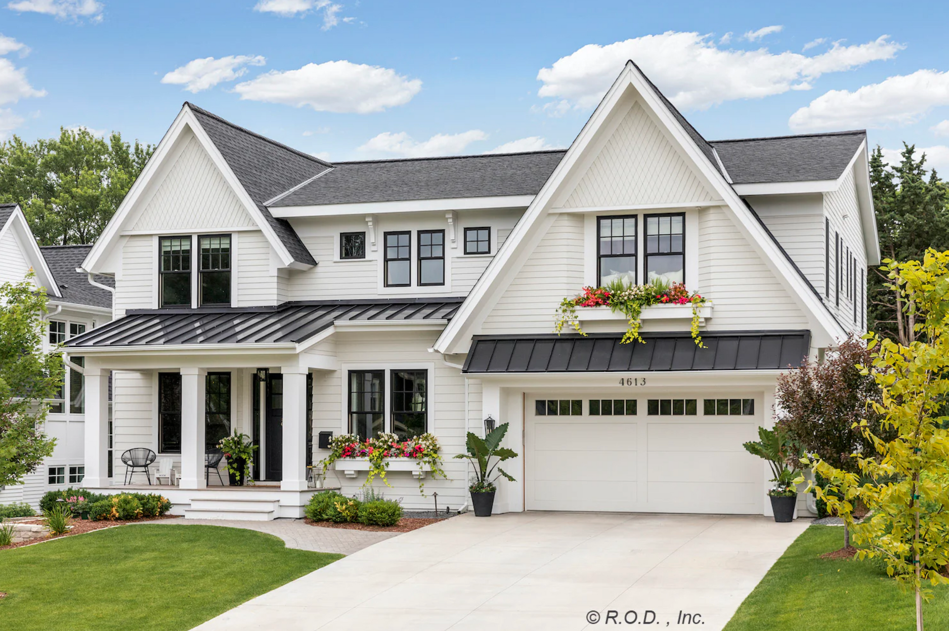 A large white house with a black roof and a black garage door.