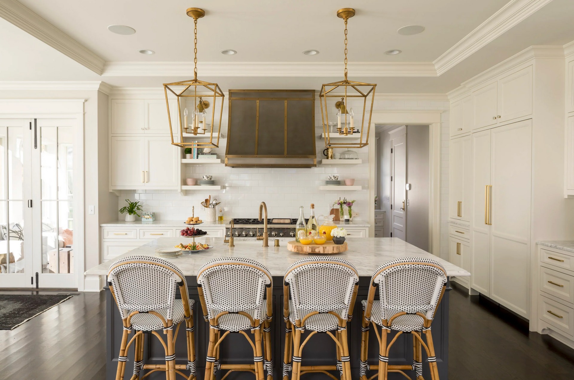 A kitchen with a large island and wicker chairs.