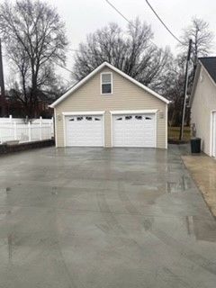 A garage with two garage doors and a concrete driveway in front of it.