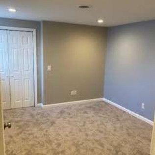 An empty room with a carpeted floor and a closet.