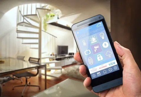 A person is holding a smart phone in their hand in a living room.
