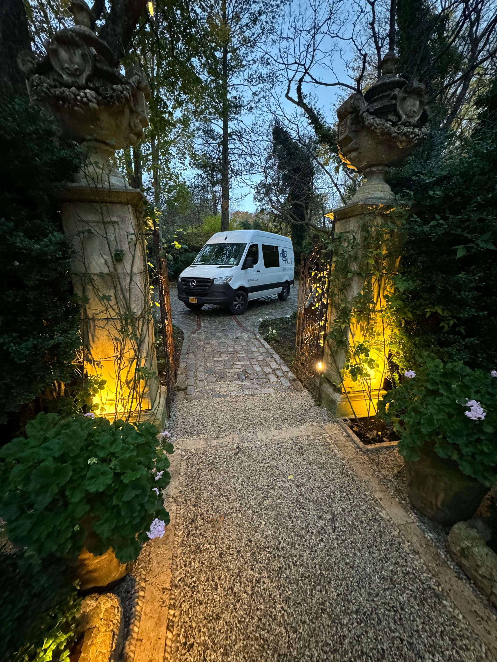 A white van is parked in the middle of a gravel driveway.