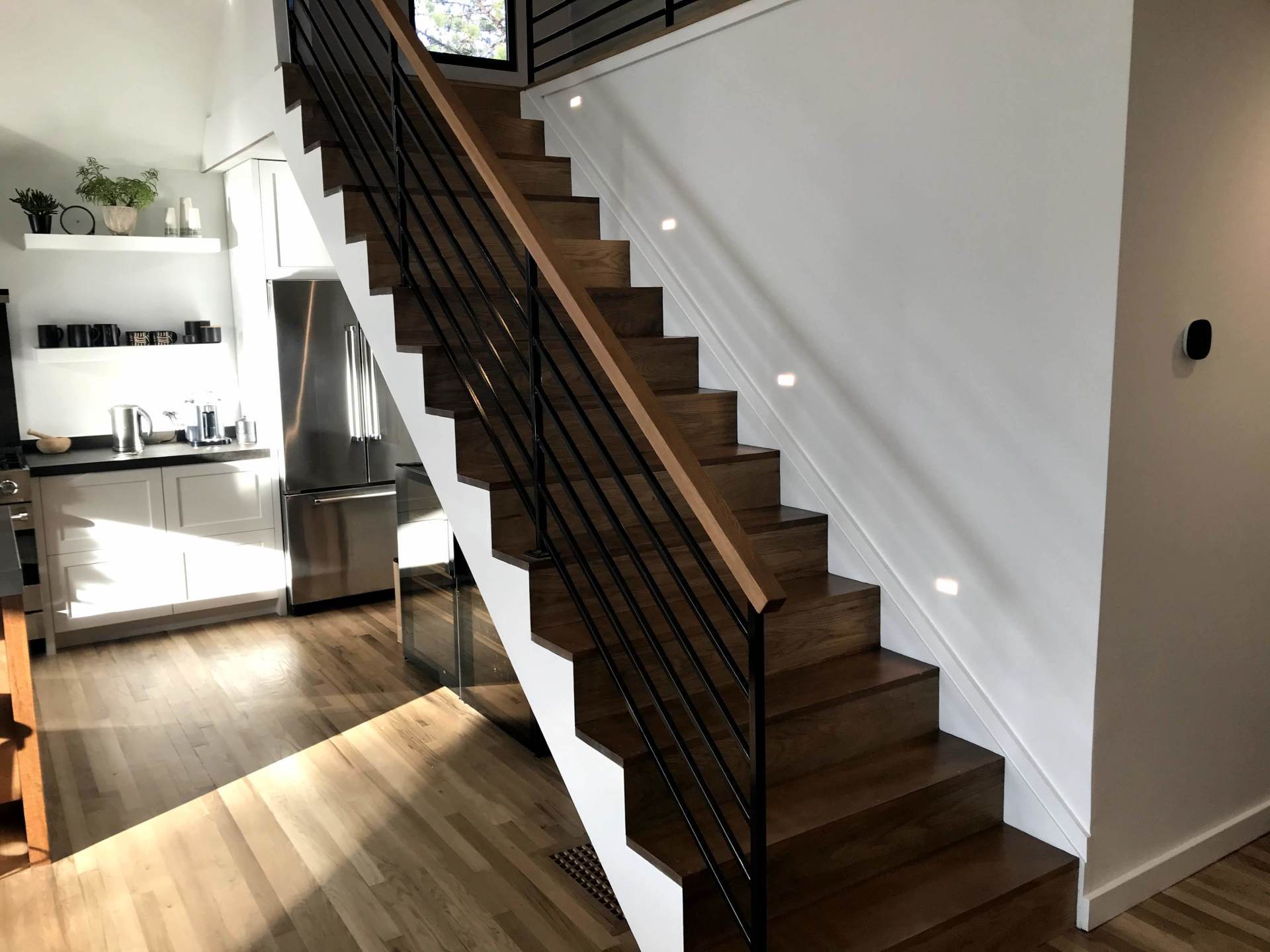 A wooden staircase with a black railing in a kitchen