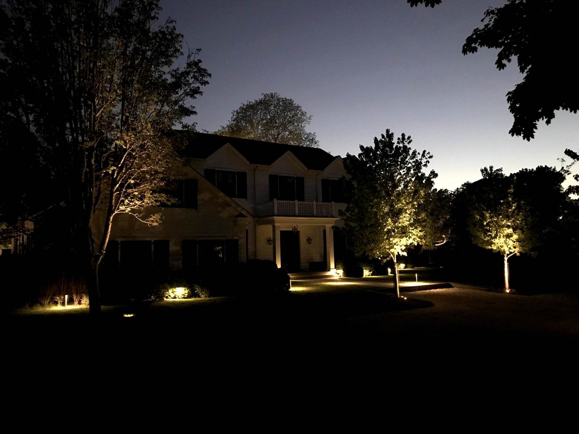 A house is lit up at night with trees in front of it