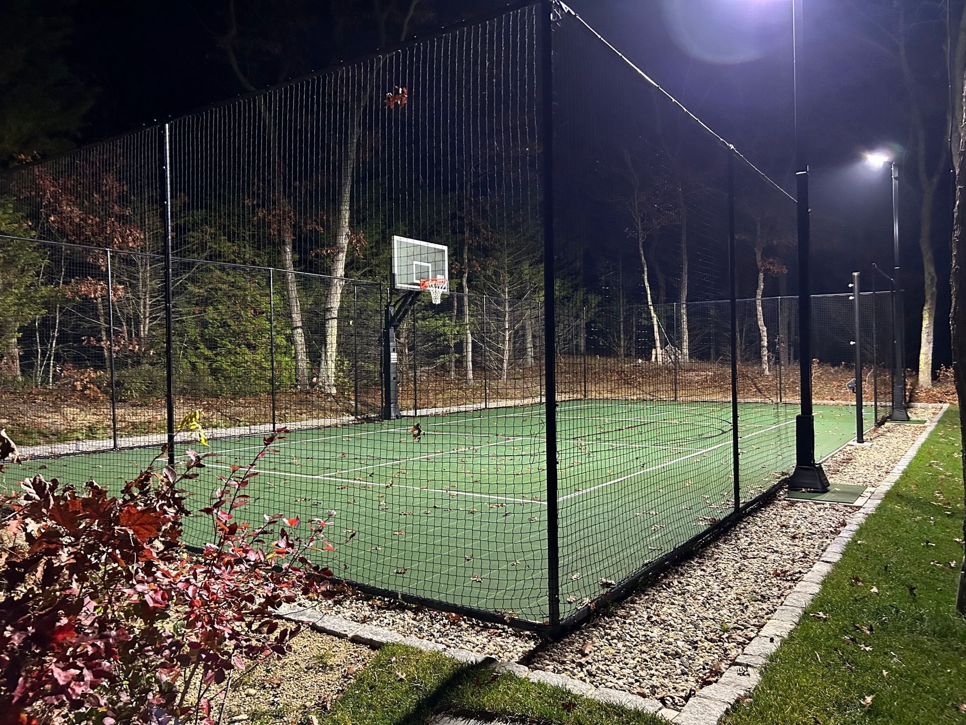 A basketball court with a fence around it at night.