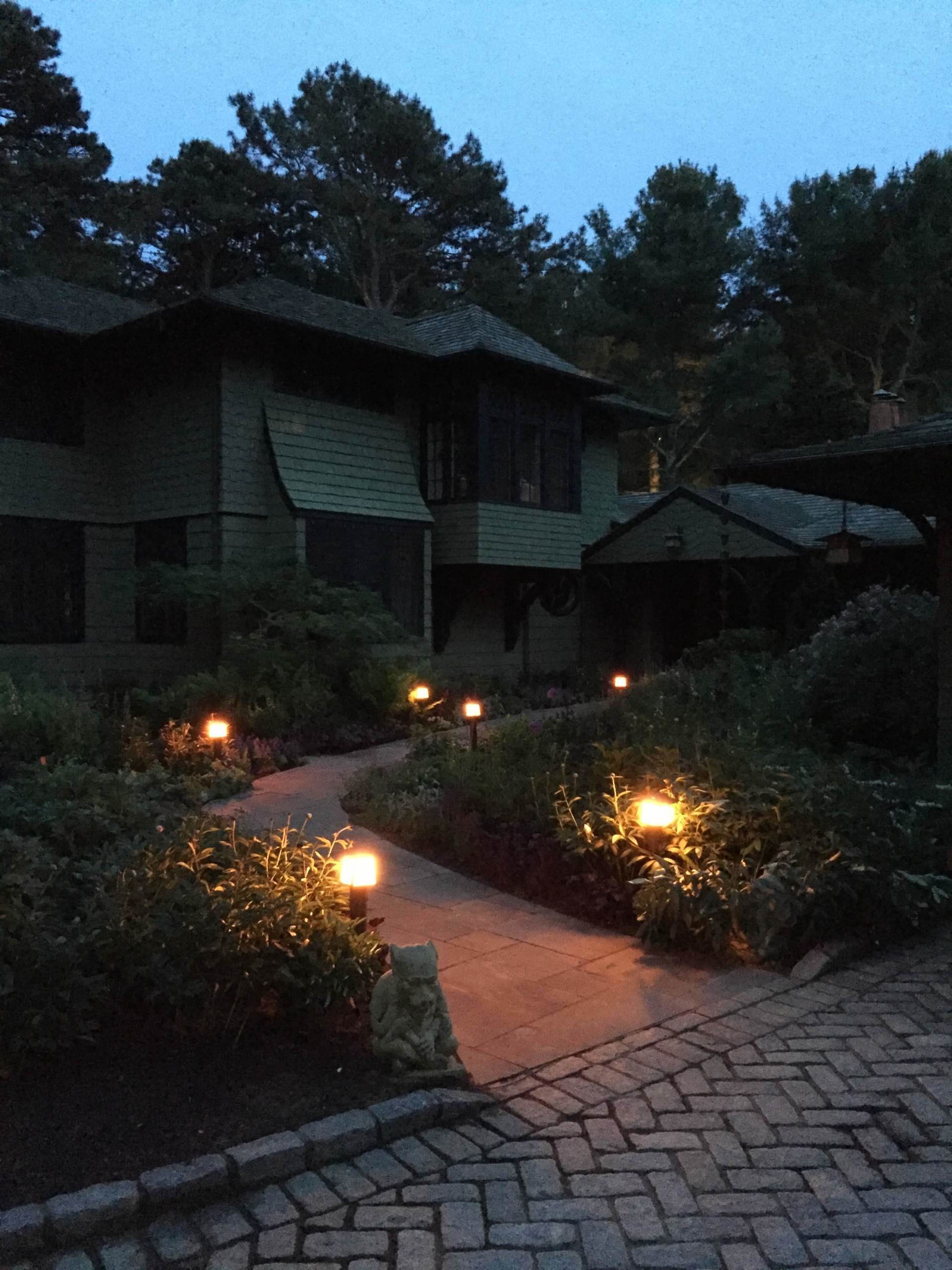 A brick walkway leading to a house at night