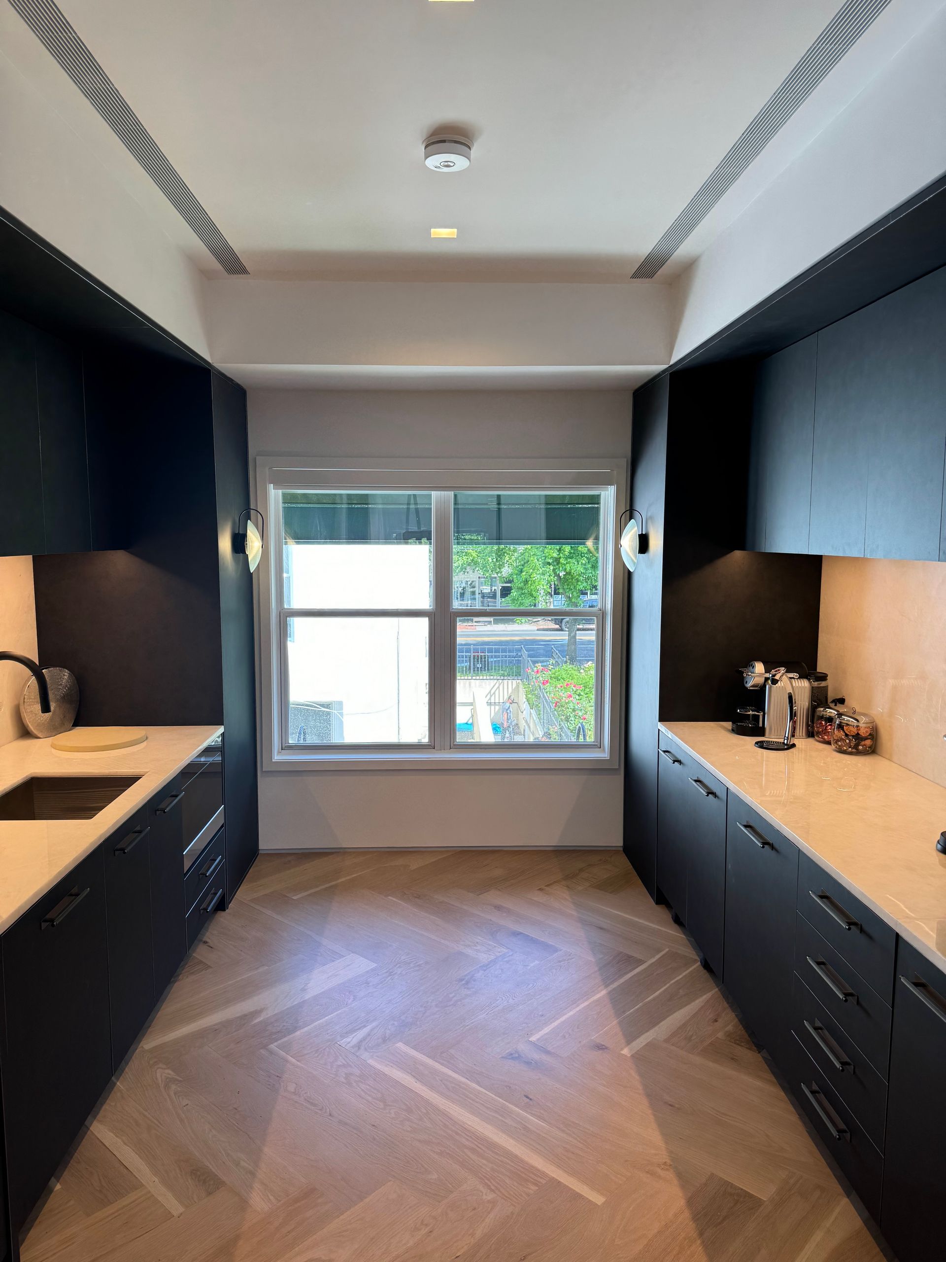 A kitchen with black cabinets and a large window.