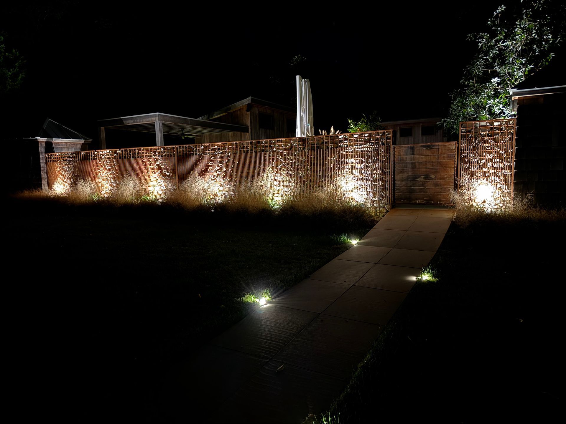 A brick wall is lit up at night with a walkway leading to it.