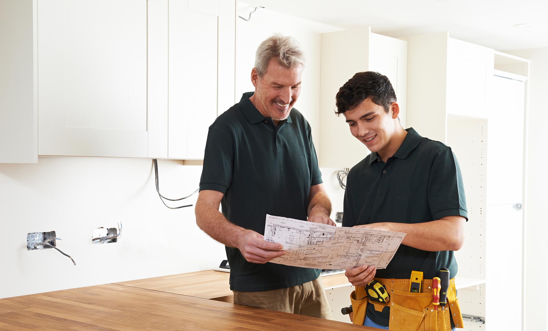 Two men are looking at a map in a kitchen.