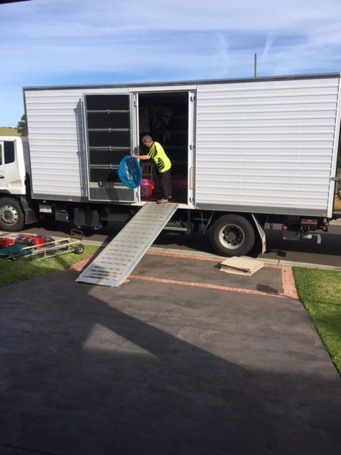 A Man Is Loading A Box Into A Moving Truck — Fairdinkum Removals In Nowra, NSW