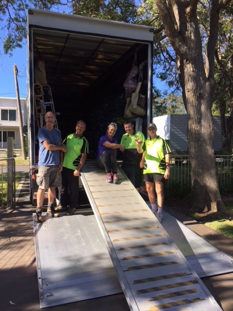 A Group Of People Are Standing In Front Of A Moving Truck — Fairdinkum Removals In Nowra, NSW