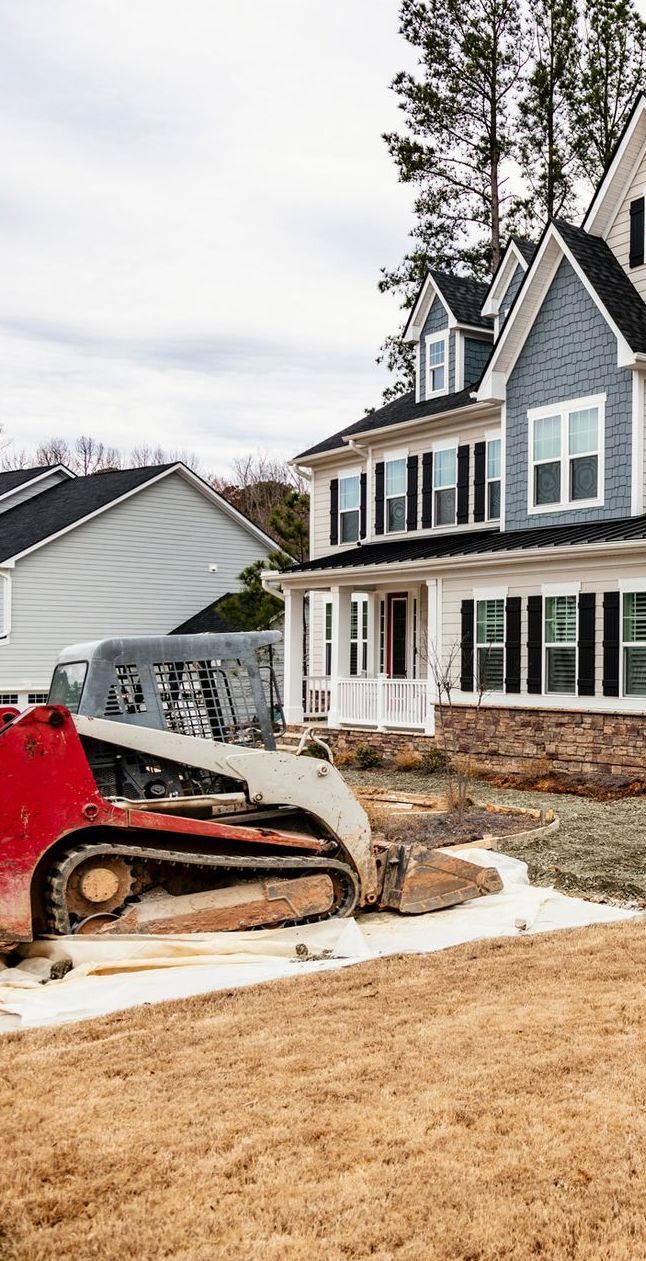 A bulldozer is sitting in front of a house.