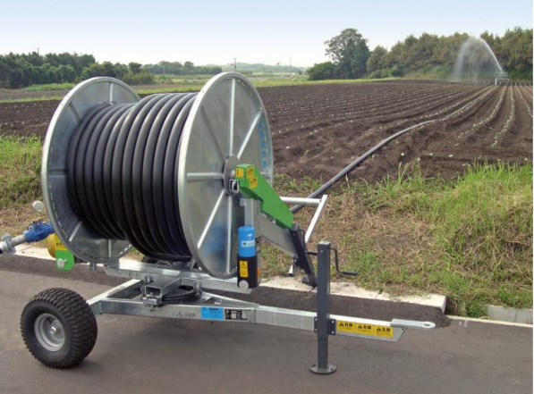 A hose reel is sitting on a trailer in a field