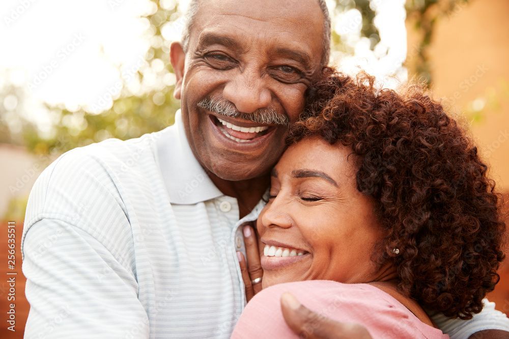 A man and a woman are hugging each other and smiling.