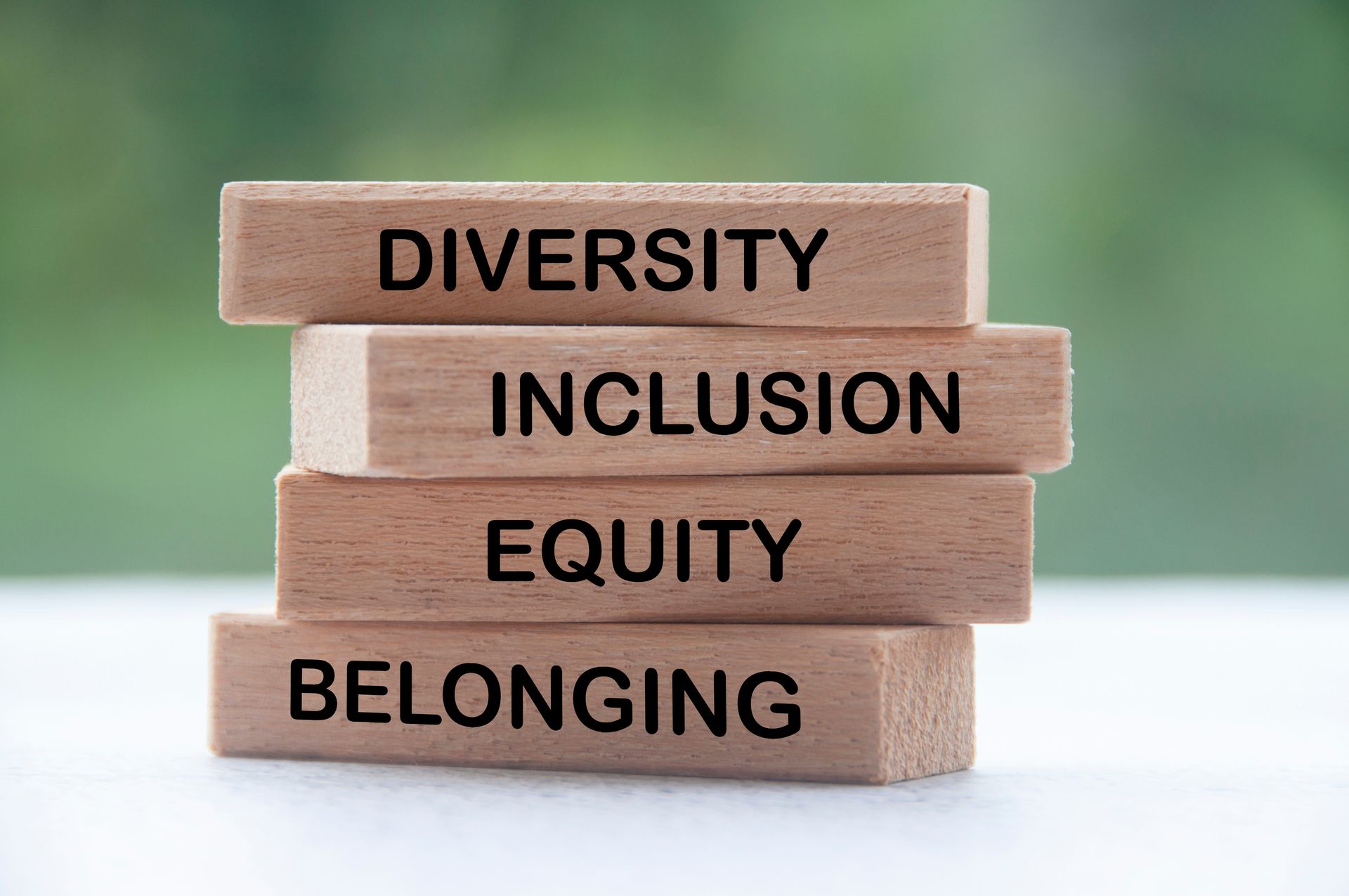 A stack of wooden blocks with the words diversity inclusion equity belonging written on them.