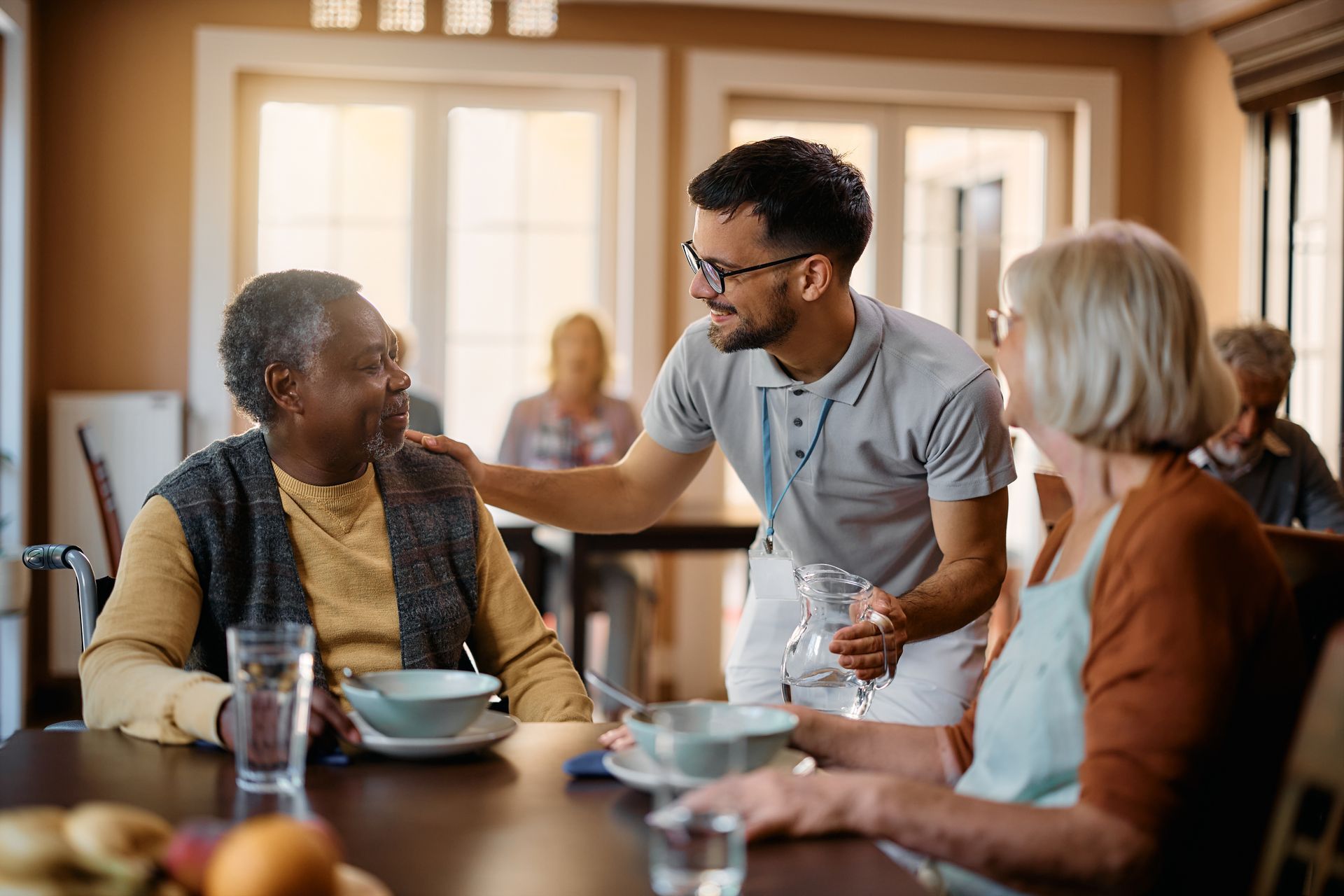 A man is talking to a group of elderly people sitting at a table.