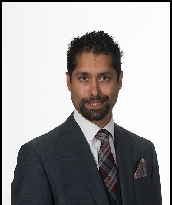 A man in a suit and tie is smiling for the camera