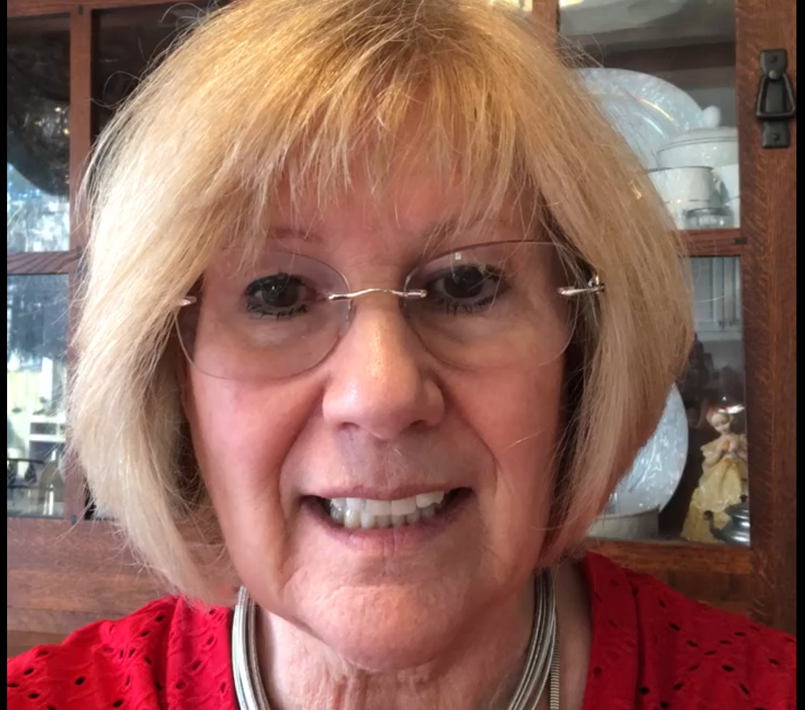 A woman wearing glasses and a red shirt is smiling