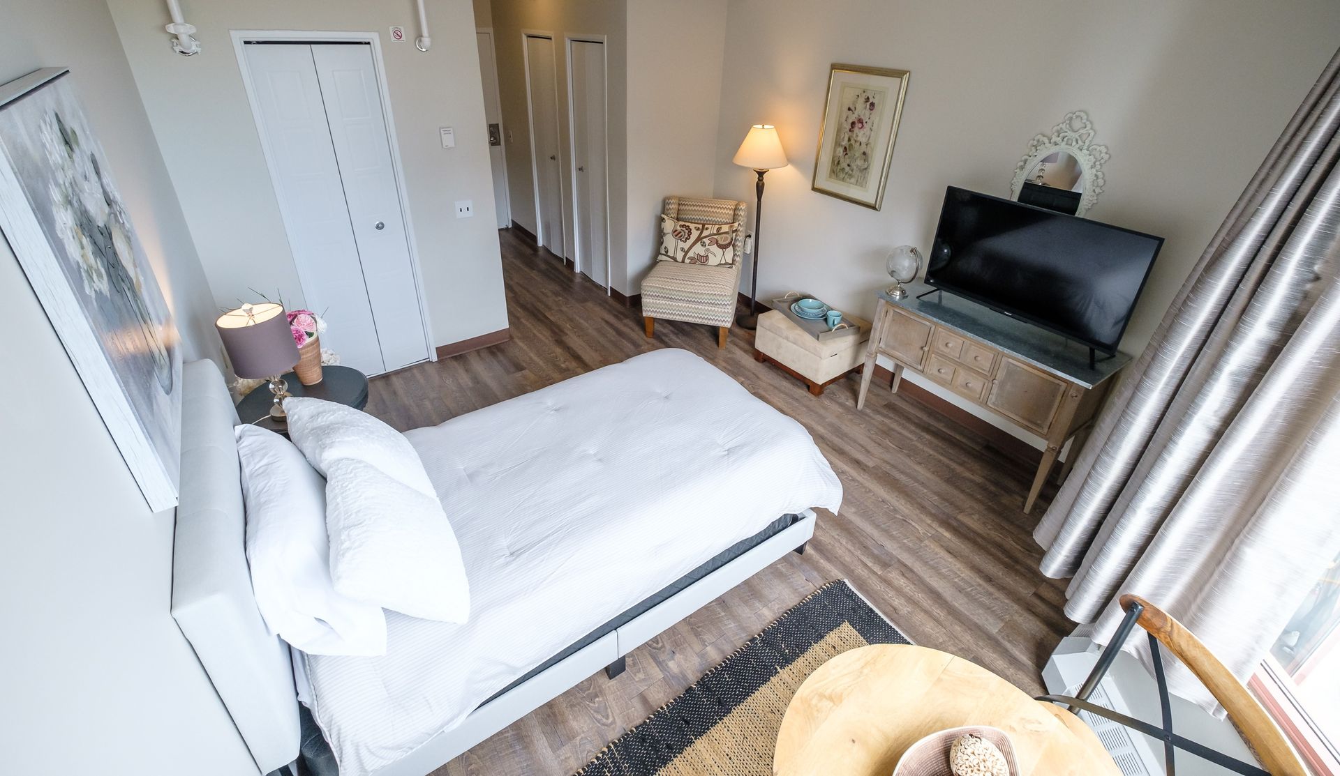 A bedroom with a bed , chair , television and a table.