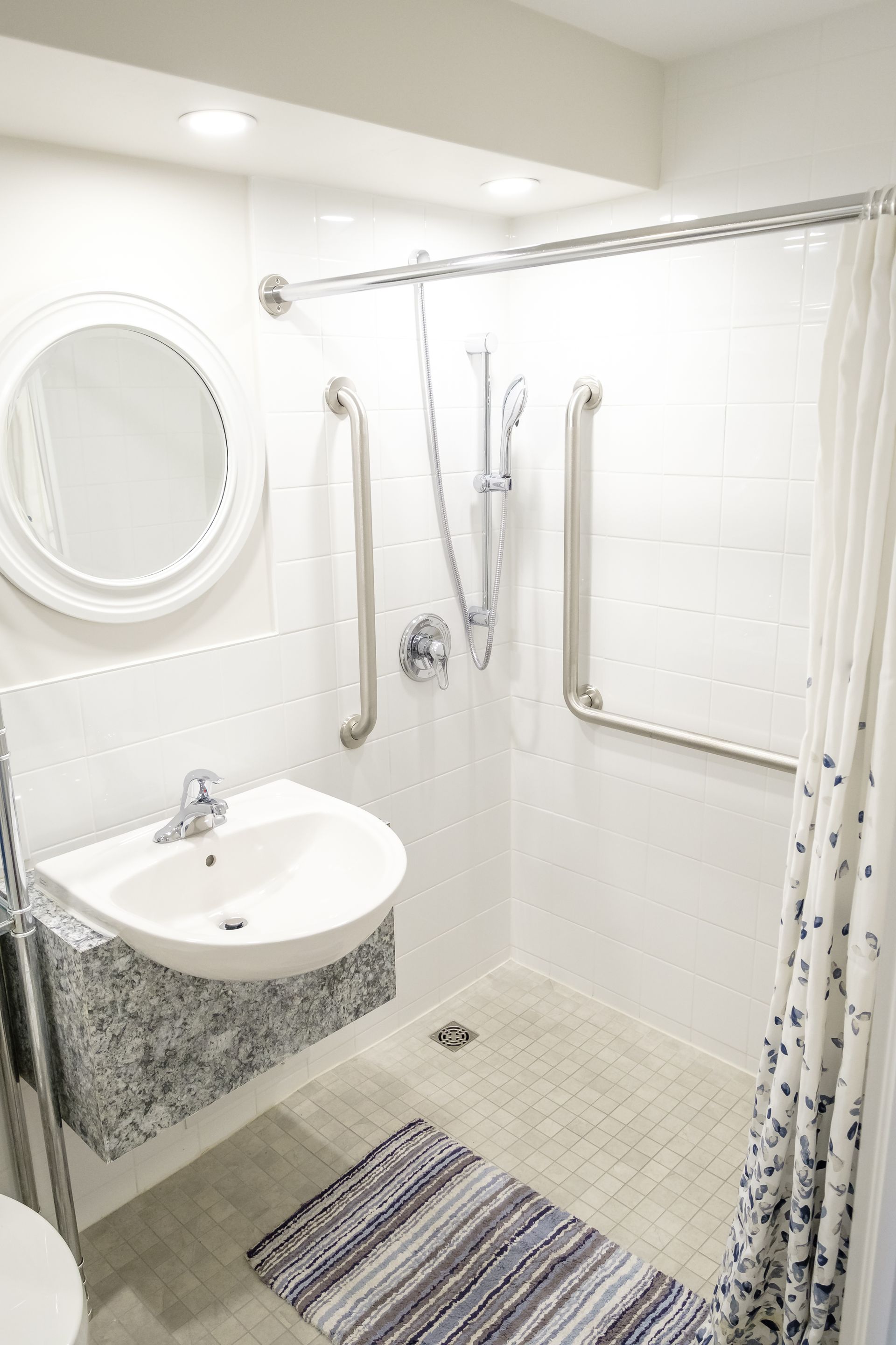 A bathroom with a sink , toilet , shower and mirror.
