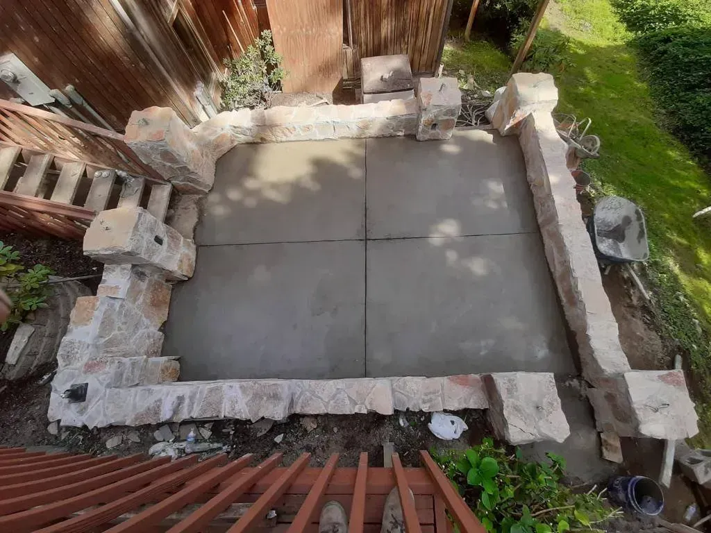 Concrete patio enclosed by stone walls and pillars.