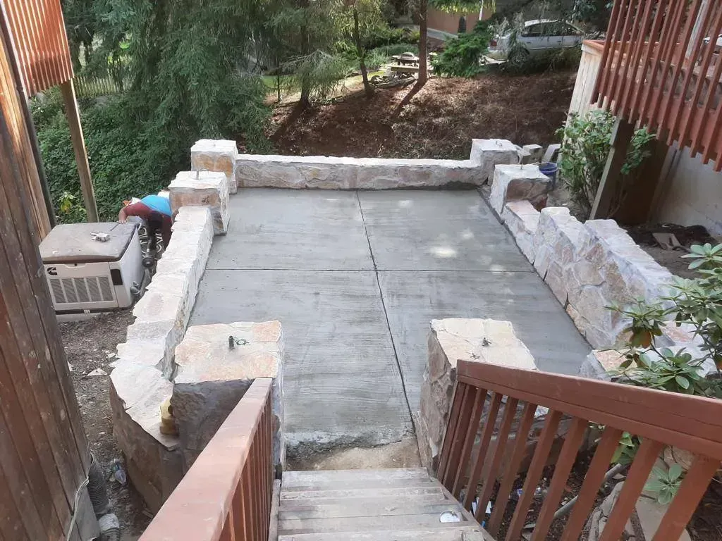 Stone patio under construction with stairs leading down. Two workers are present.