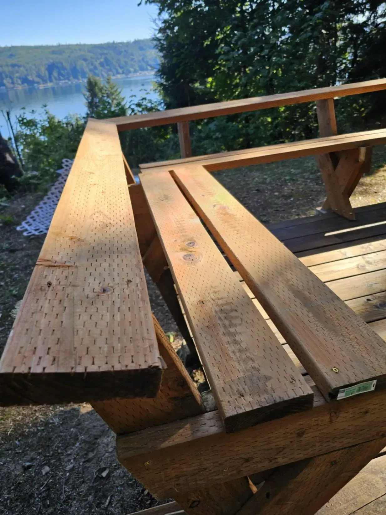 Wooden deck overlooking a lake with lumber on it, under construction.